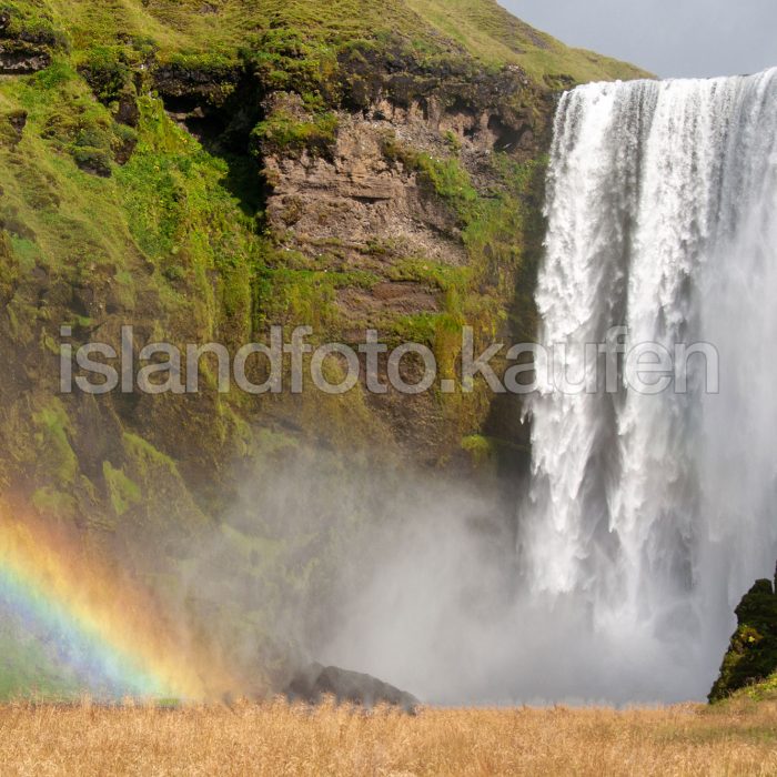 Halber Regenbogen vor einem Wasserfall